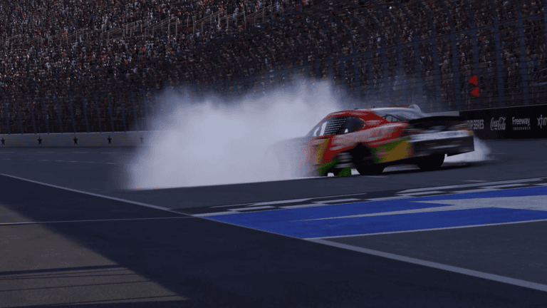 NASCAR 26 nighttime victory burnout showing a red Cup Series car spinning tires near the start-finish line with star-decorated pit wall and crowd in the stands