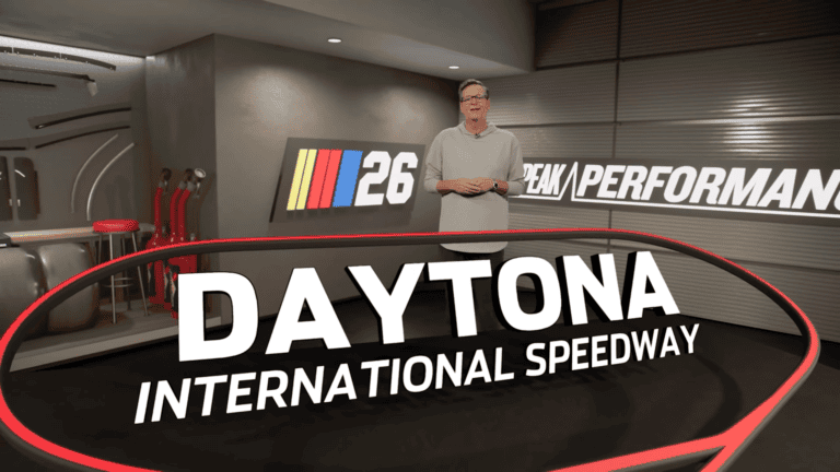 NASCAR 26 promotional screenshot showing a host presenting Daytona International Speedway in a Peak Performance garage studio setting with the NASCAR 26 logo